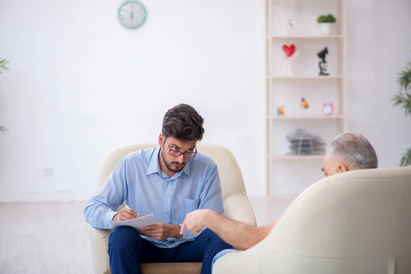 Velho visitando jovem psicoterapeuta masculino — Fotografia de Stock