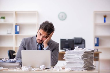 Genç bir erkek çalışan ve ofiste çok fazla iş var.