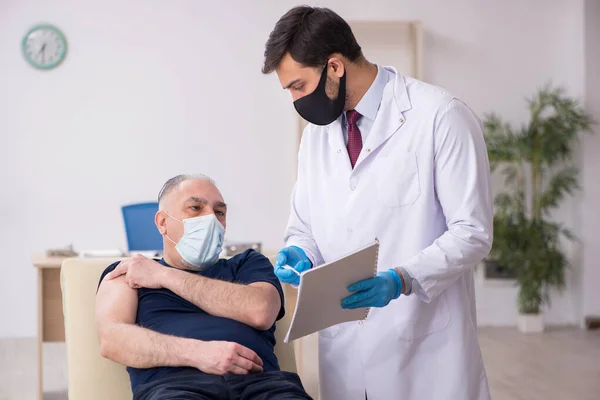 Vieux patient de sexe masculin visitant un jeune médecin en conce de vaccination — Photo