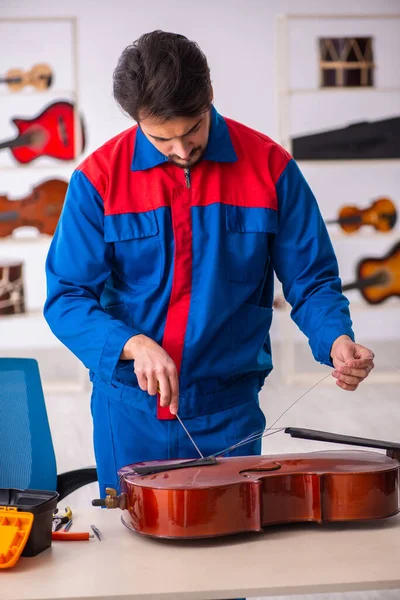 Jovem reparador do sexo masculino reparando instrumentos musicais no local de trabalho — Fotografia de Stock