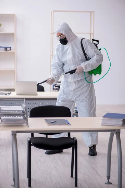 Jovem empreiteiro masculino desinfetando escritório durante pandemia — Fotografia de Stock