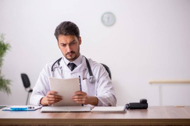 Klinikte çalışan genç erkek doktor.