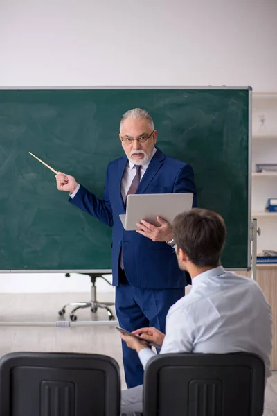 Viejo profesor masculino y joven estudiante masculino delante del tablero verde —  Fotos de Stock