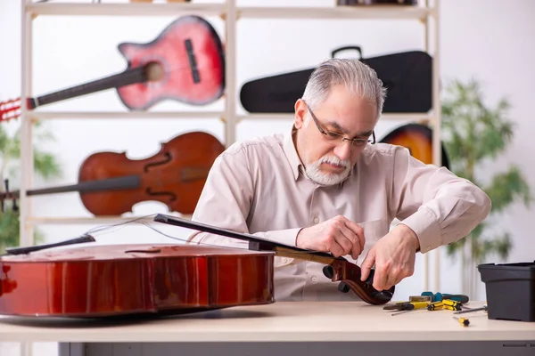 Vieux réparateur masculin réparant des instruments de musique sur le lieu de travail — Photo