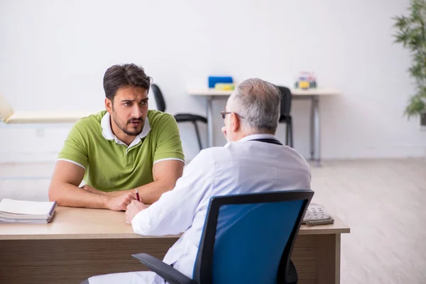 Jovem visitando velho médico masculino — Fotografia de Stock