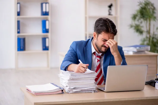 Jovem funcionário masculino e muito trabalho no escritório — Fotografia de Stock