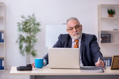 Ofiste çalışan yaşlı bir erkek.
