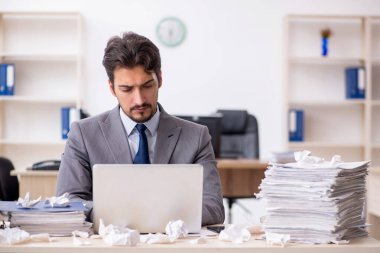 Genç bir erkek çalışan ve ofiste çok fazla iş var.