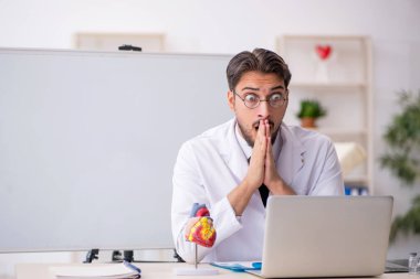 Sınıfta oturan genç erkek kardiyolog.