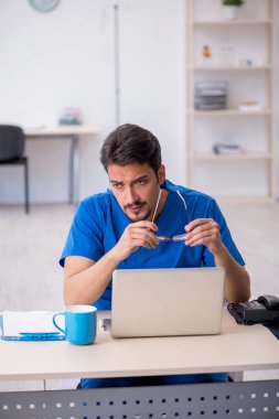 Klinikte çalışan genç erkek doktor.