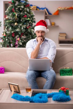 Genç adam Noel 'i evde yalnız kutluyor.