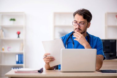 Klinikte çalışan genç erkek doktor.