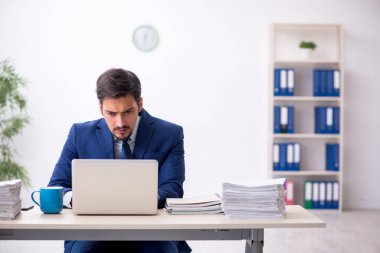 Genç bir erkek çalışan ve ofiste çok fazla iş var.