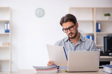 Genç erkek çalışan ofiste oturuyor.