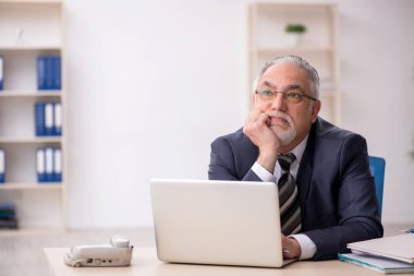 Ofiste çalışan yaşlı bir erkek.