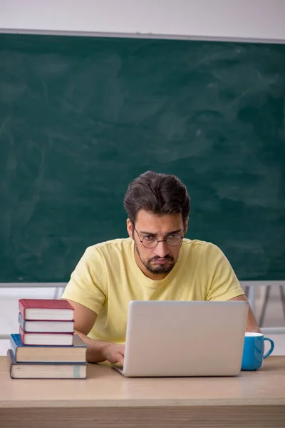 Jonge mannelijke student bereidt zich voor op examens in de klas — Stockfoto