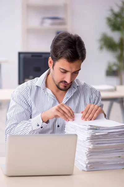 Joven empleado masculino y demasiado trabajo en la oficina — Foto de Stock