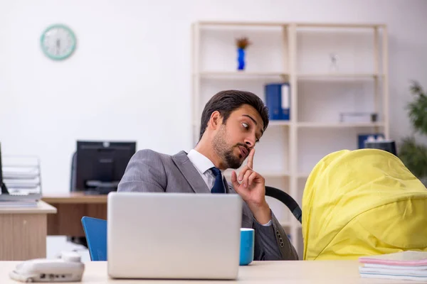 Young male employee looking after new born at workplace — Stock Photo, Image