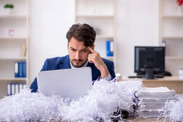 Jeune employé masculin et beaucoup de papiers coupés dans le bureau — Photo