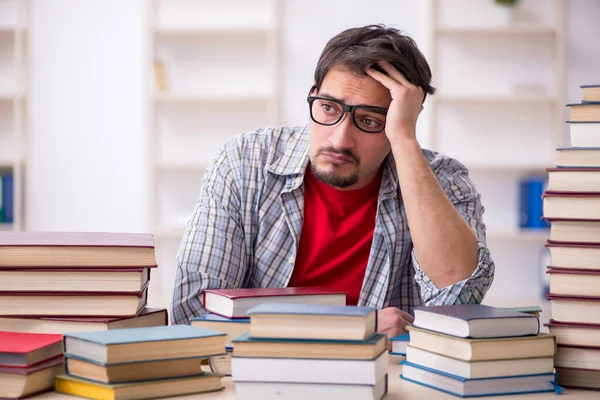 Giovane studente maschio e troppi libri in classe — Foto Stock