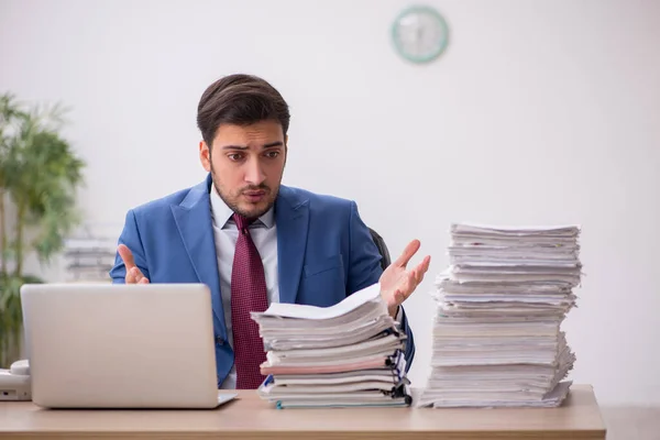 Ung manlig anställd och för mycket arbete på kontoret — Stockfoto