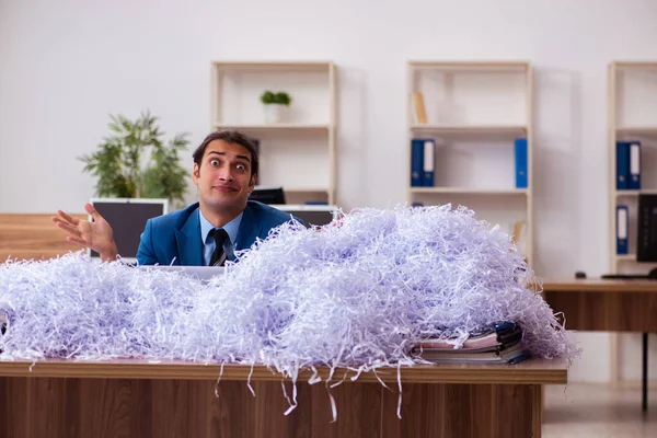 Fiatal férfi alkalmazott és sok kivágott papír az irodában. — Stock Fotó