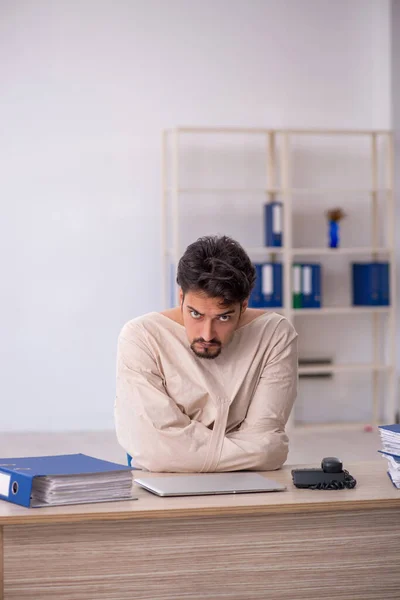 Crazy young man in straitjacket at the office — Stock Photo, Image