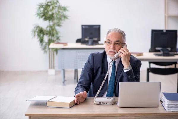 Viejo empleado hablando por teléfono en el lugar de trabajo —  Fotos de Stock
