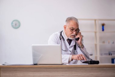 Hastanede çalışan yaşlı erkek doktor.