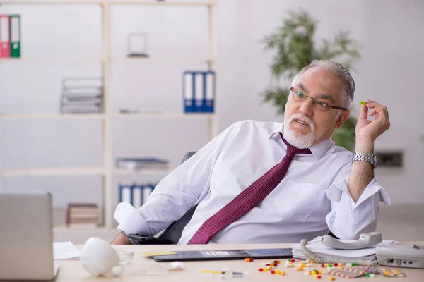 Vecchio dipendente tossicodipendente seduto in ufficio — Foto Stock