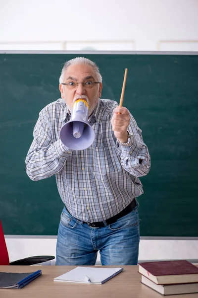 Régi férfi tanár kezében hangosbeszélő az osztályteremben — Stock Fotó