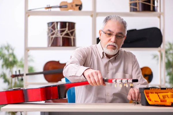 Vecchio riparatore di sesso maschile che ripara strumenti musicali sul posto di lavoro — Foto Stock