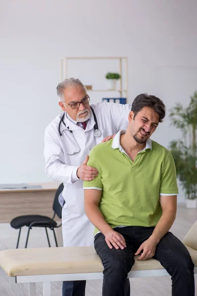 Genç erkek hasta yaşlı erkek doktoru ziyaret ediyor. — Stok fotoğraf