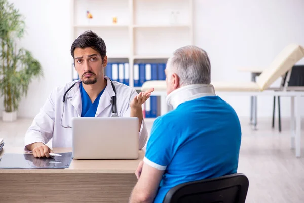 Viejo cuello lesionado paciente masculino visitando joven médico masculino — Foto de Stock