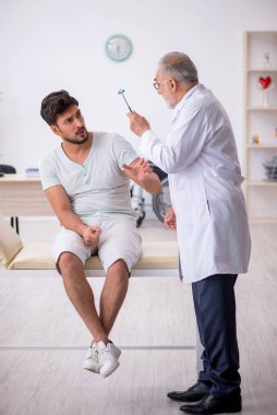 Genç erkek hasta yaşlı erkek nörologu ziyaret ediyor.