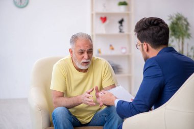 Yaşlı adam genç erkek psikoterapisti ziyaret ediyor.