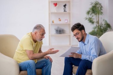 Yaşlı adam genç erkek psikoterapisti ziyaret ediyor.