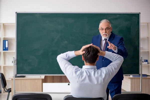 Viejo profesor masculino y joven estudiante masculino delante del tablero verde —  Fotos de Stock