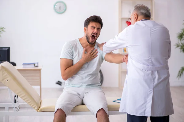 Junge männliche Patientin besucht alten männlichen Arzt — Stockfoto