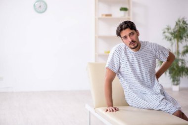 Genç erkek hasta hastanede doktor bekliyor.