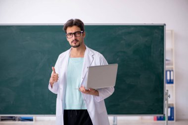 Tahtanın önündeki genç erkek kimyager.