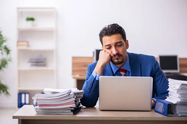 Giovane dipendente maschio infelice con un lavoro eccessivo sul posto di lavoro — Foto Stock