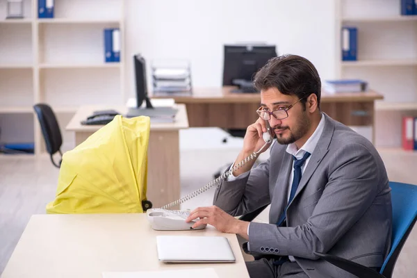 Young male employee looking after new born at workplace — Stock Photo, Image