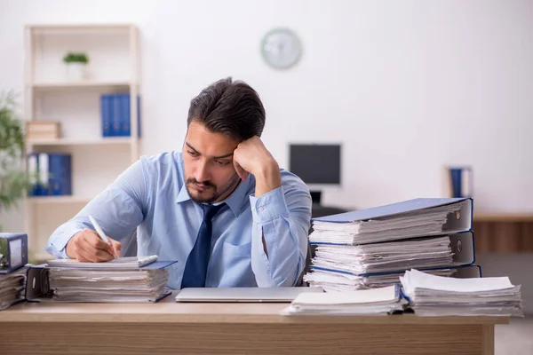 Joven empleado masculino y demasiado trabajo en la oficina — Foto de Stock