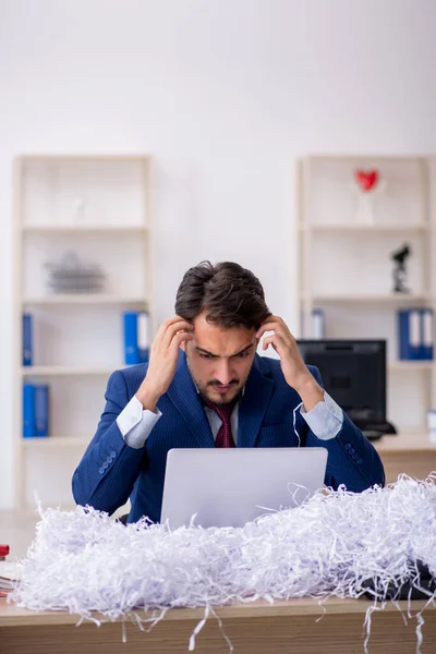 Joven empleado masculino y muchos papeles cortados en la oficina — Foto de Stock