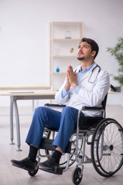 Klinikte çalışan tekerlekli sandalyedeki genç erkek doktor.