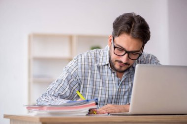 Genç erkek çalışan ofiste oturuyor.