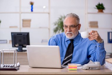 Eski erkek çalışanımız teneffüste kahve içiyor.