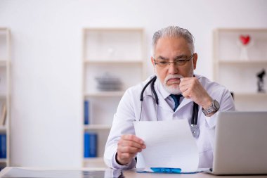 Klinikte çalışan yaşlı erkek doktor.