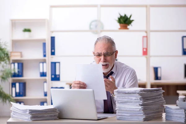 Velho empregado masculino e muito trabalho no escritório — Fotografia de Stock